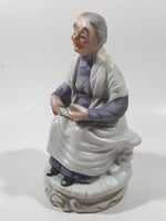 Old Woman Sitting with Basket of Bread Holding a Pear and Banana 6 1/2" Tall Porcelain Figurine