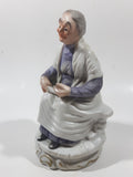 Old Woman Sitting with Basket of Bread Holding a Pear and Banana 6 1/2" Tall Porcelain Figurine