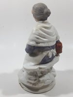 Old Woman Sitting with Basket of Bread Holding a Pear and Banana 6 1/2" Tall Porcelain Figurine