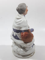 Old Woman Sitting with Basket of Bread Holding a Pear and Banana 6 1/2" Tall Porcelain Figurine