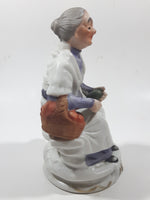 Old Woman Sitting with Basket of Bread Holding a Pear and Banana 6 1/2" Tall Porcelain Figurine