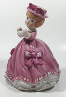 Vintage Girl in Pink Dress with Bows Wearing a Hat Holding Pen and Paper 7" Ceramic Wind Up Musical Figurine